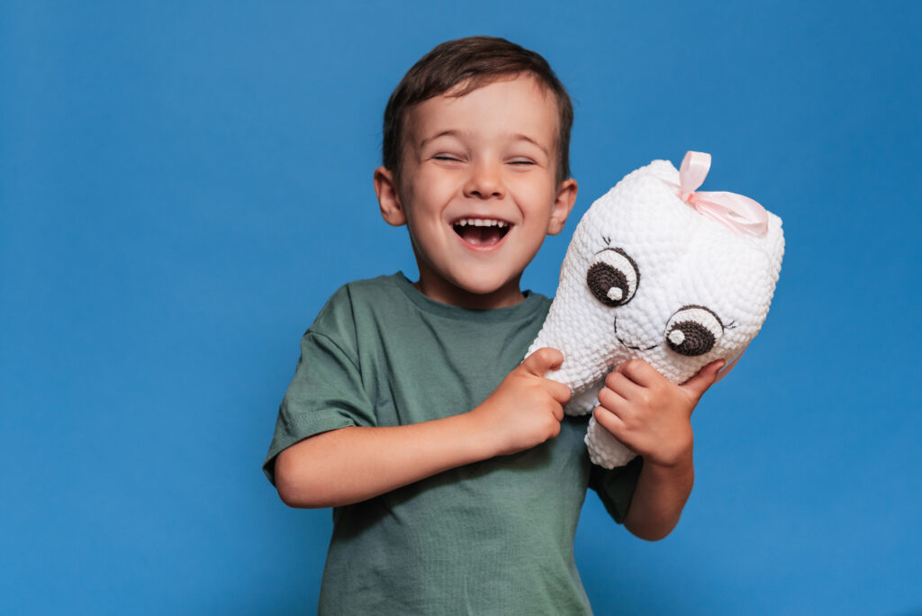 Boy smiling and hugging a plush tooth toy